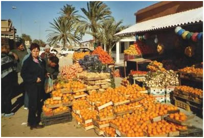 Ghislaine devant un marché de fruits et légumes
